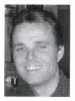 Description de l'image par IA : Homme souriant, cheveux courts, portant une chemise à col.