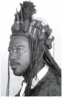 Description de l'image par IA : Homme avec une coiffe traditionnelle africaine, cheveux longs, regard sérieux.