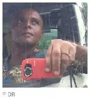 Description de l'image par IA : Homme tenant un appareil photo rouge depuis une voiture.