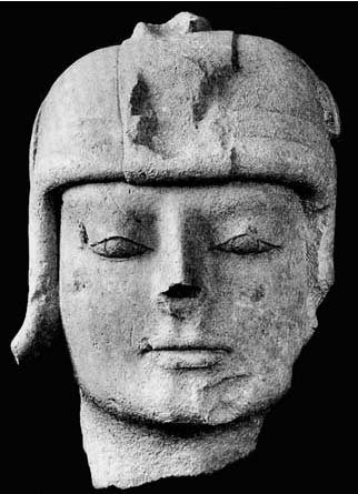 Description de l'image par IA : Tête de guerrier casquée en pierre, yeux clos, expression sereine.