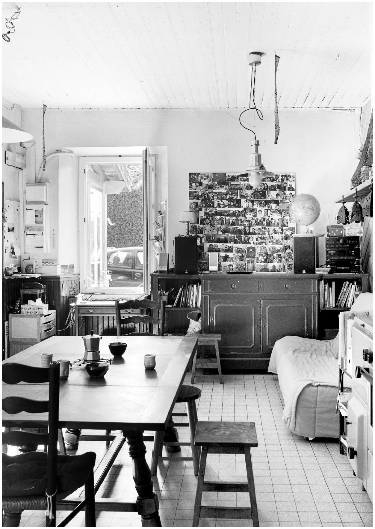 Description de l'image par IA : Salle à manger avec table, chaises, buffet, livres, et porte ouverte sur jardin.