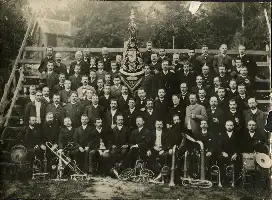 Description de l'image par IA : Groupe d'hommes en costumes sombres avec instruments de musique, bannière et drapeaux.