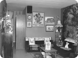 Description de l'image par IA : Salon avec canapé, table basse, lampes, tableaux et bibelots. Décoration vintage années 1970.