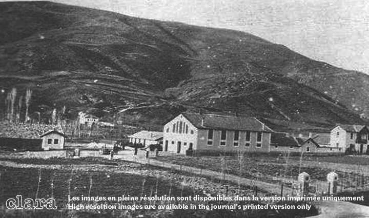 Image description generated by AI: Black and white image of a rural agricultural farm with buildings and hills.