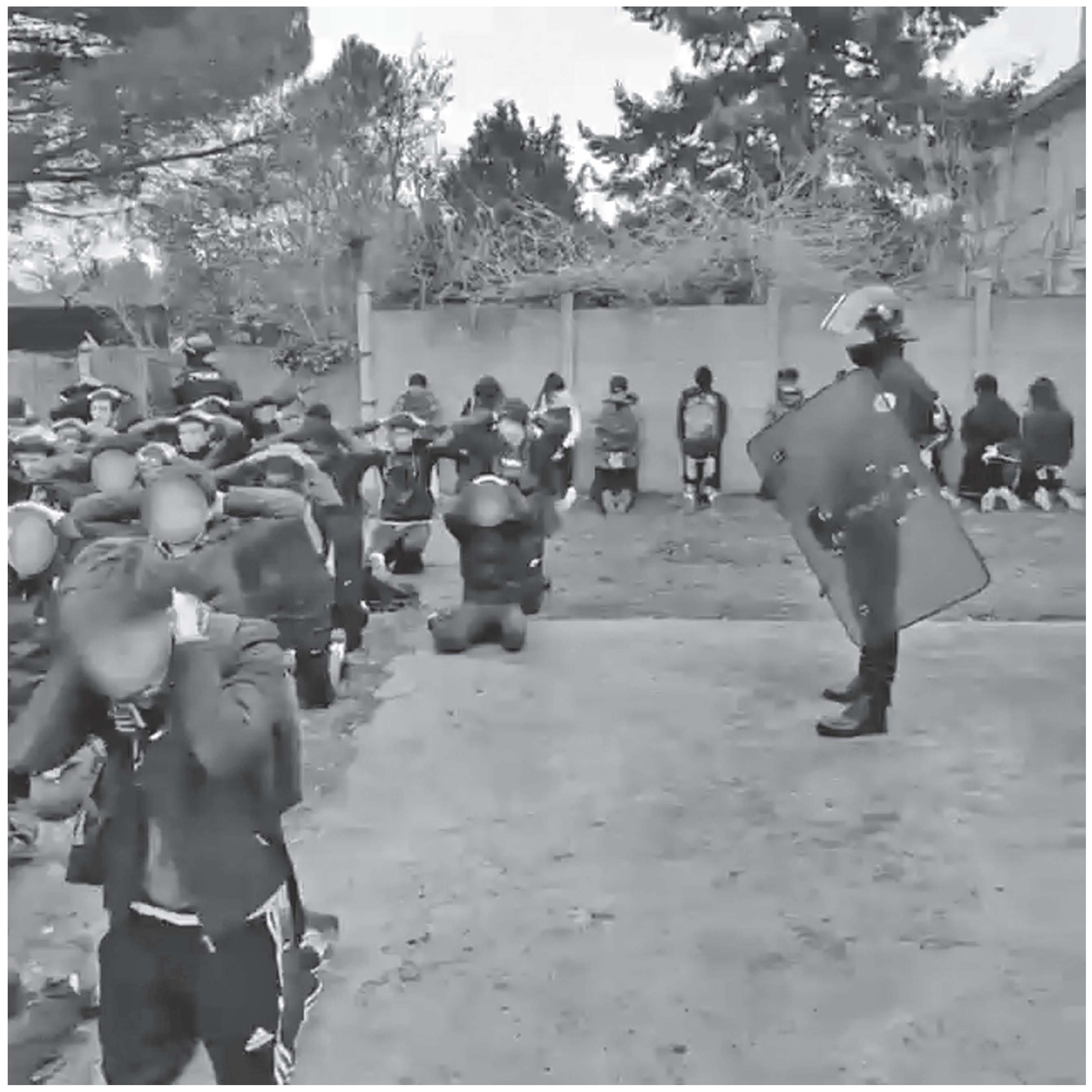 Description de l'image par IA : Des lycéens à terre, encerclés par des policiers en uniforme, certains tenant des boucliers.