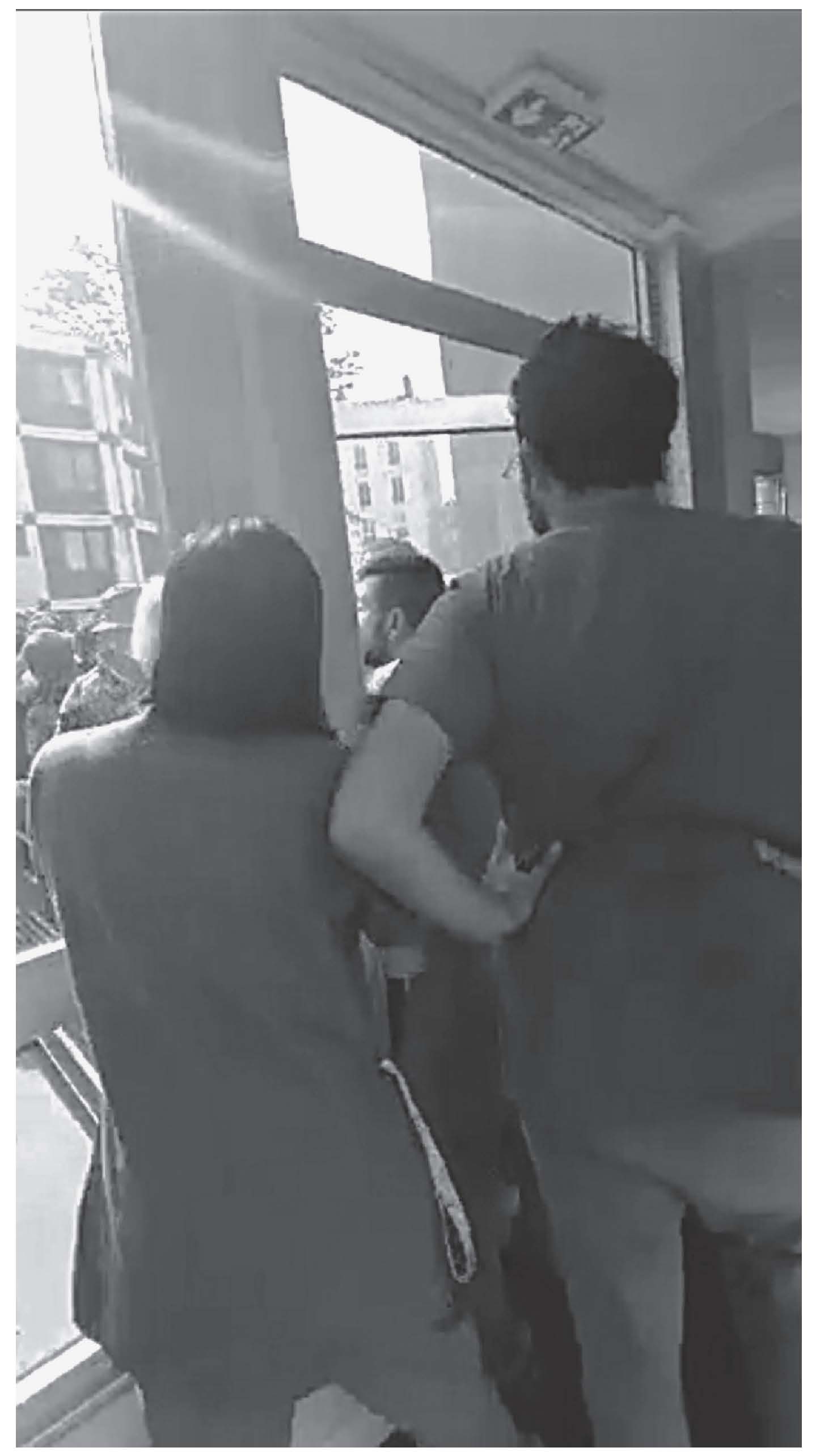 Description de l'image par IA : Trois personnes debout près d'une fenêtre, l'une d'elles tenant un enfant.