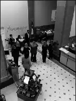 Description de l'image par IA : Un groupe de personnes visite une bibliothèque, observant des expositions et discutant dans une grande salle.