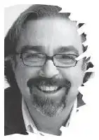 Description de l'image par IA : Homme souriant avec des lunettes et une barbe, en noir et blanc.