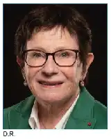Description de l'image par IA : Femme âgée aux cheveux courts et lunettes, sourire, veste verte, fond noir.