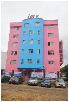 Description de l'image par IA : Bâtiment rose et bleu avec "ime" au sommet, plusieurs voitures garées devant.