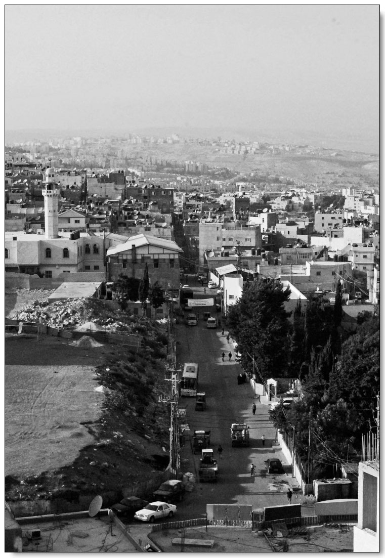 Description de l'image par IA : Ville dense avec bâtiments, voitures et une mosquée visible. Vue depuis une entrée principale.