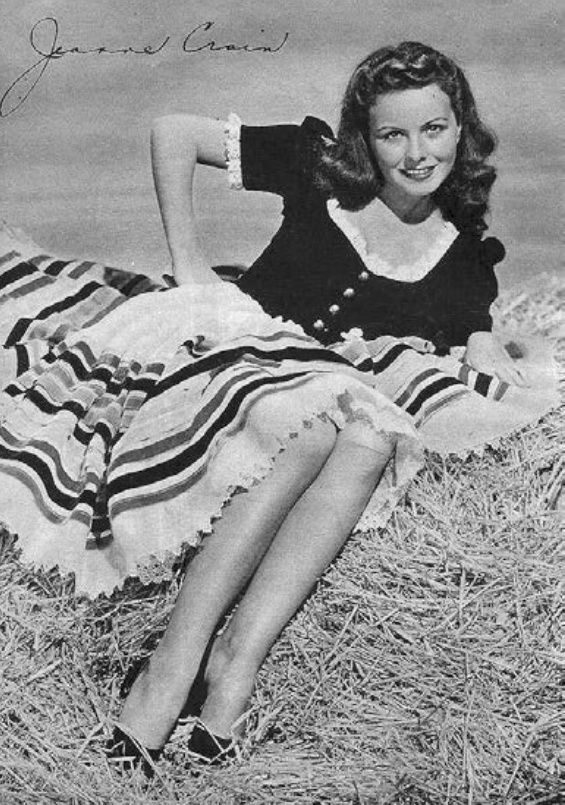 Description de l'image par IA : Jeune femme allongée dans l'herbe, souriant, portant une robe à manches courtes et une jupe à rayures.