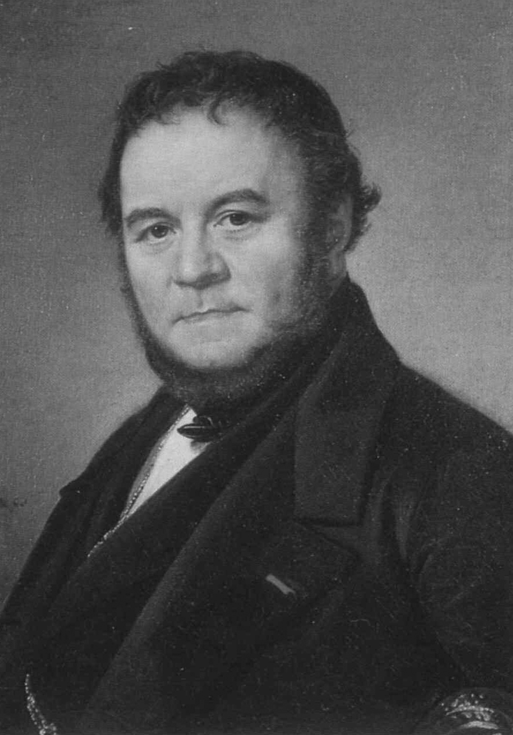 Description de l'image par IA : Homme en costume sombre, regard sérieux, cheveux courts et bouclés.
