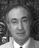 Description de l'image par IA : Portrait en noir et blanc d'un homme âgé avec des cheveux gris, portant une veste et une cravate, devant un motif géométrique.