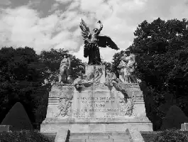 Description de l'image par IA : Monument aux morts avec statue d'ange et figures, entouré d'arbres.