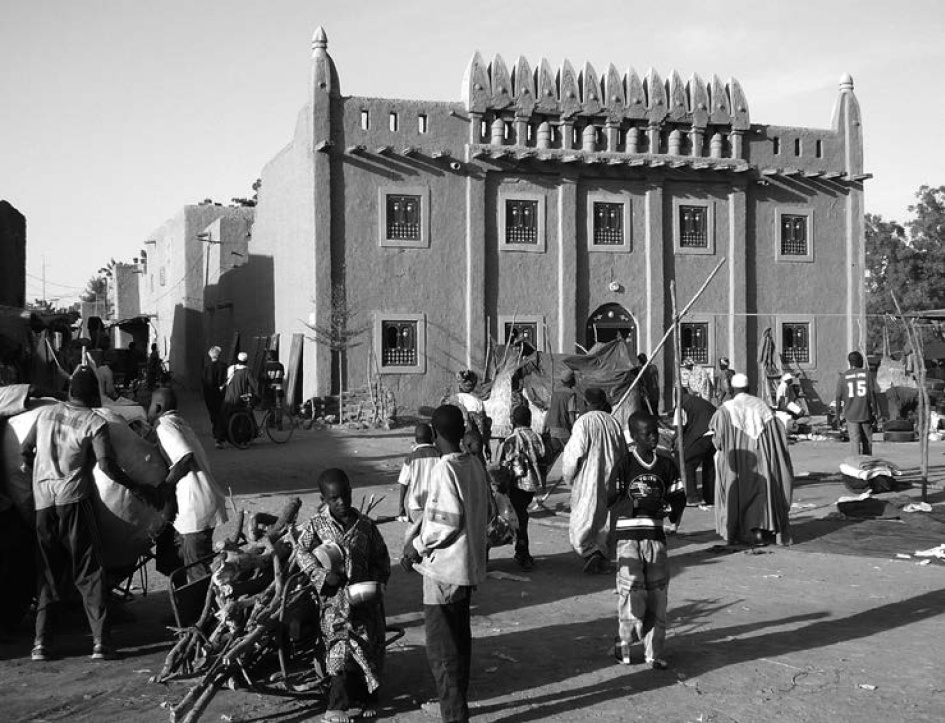 Description de l'image par IA : Marché animé devant un grand bâtiment avec des gens vendant et achetant des articles.