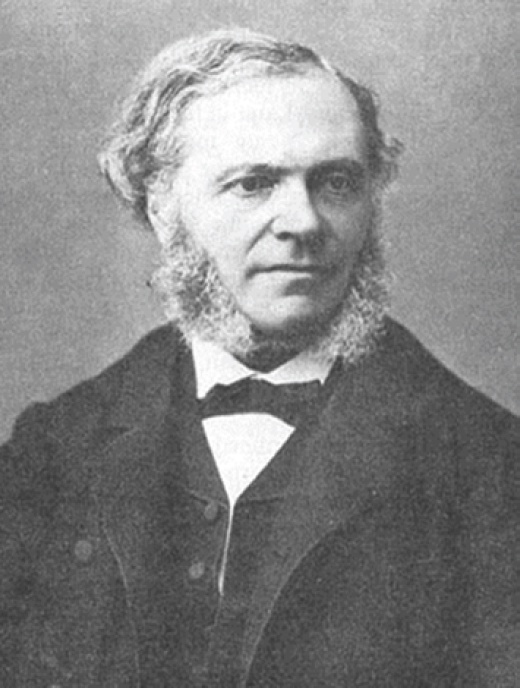 Description de l'image par IA : Portrait en noir et blanc d'un homme avec une barbe et des cheveux bouclés, portant un costume et une cravate.