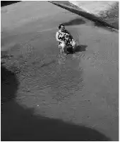 Description de l'image par IA : Femme assise sur plage, dos à la mer, avec un enfant sur les genoux.