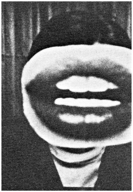 Description de l'image par IA : Visage flou en noir et blanc, bouche ouverte, dents visibles, fond sombre.