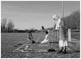 Description de l'image par IA : Quatre enfants jouent sur un grand tapis dans un parc. Un enfant tient un balai, un autre est assis, et deux autres sont debout.