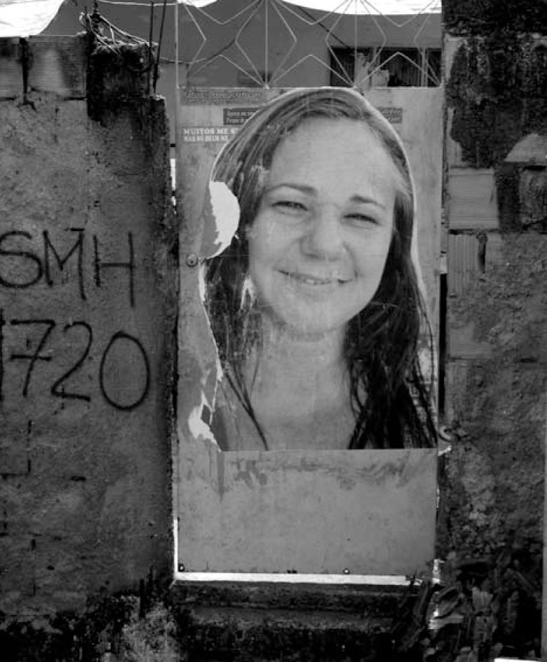 Description de l'image par IA : Photo en noir et blanc d'une jeune femme souriante sur un mur avec des graffitis.