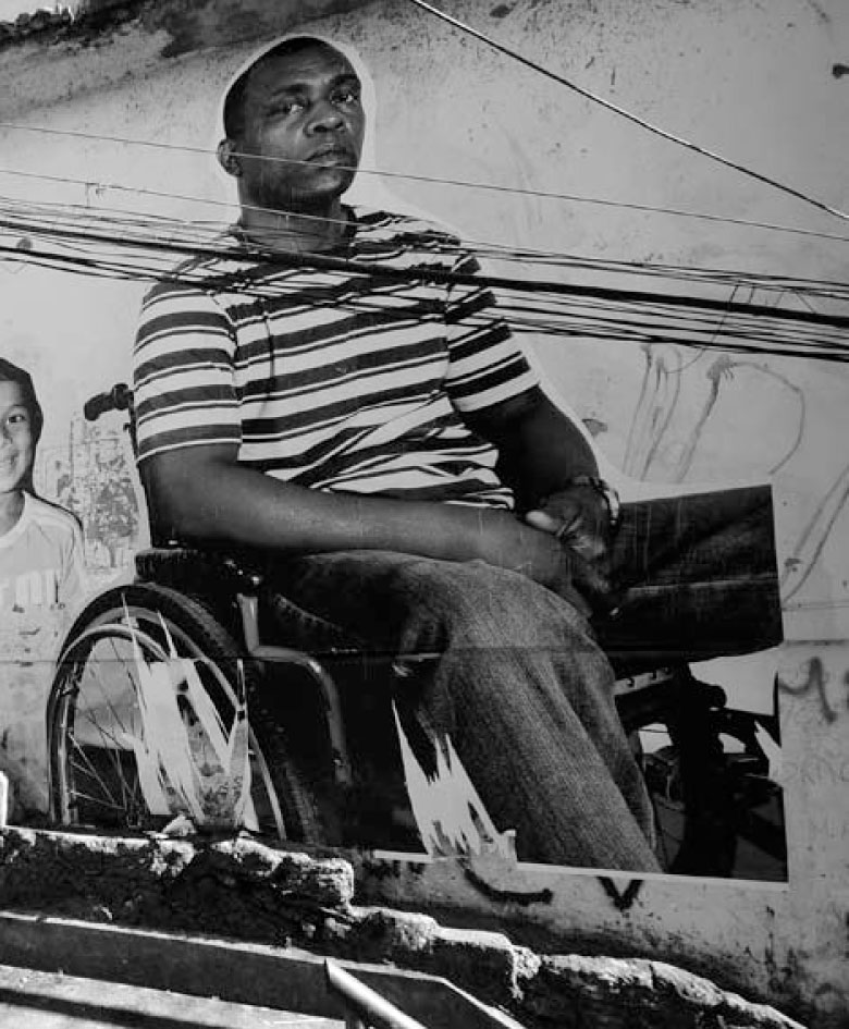 Description de l'image par IA : Homme en fauteuil roulant devant un mur avec des fils électriques.