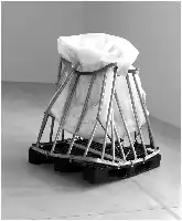 Description de l'image par IA : Un objet volumineux enveloppé dans une toile blanche, maintenu par une structure métallique sur une palette.