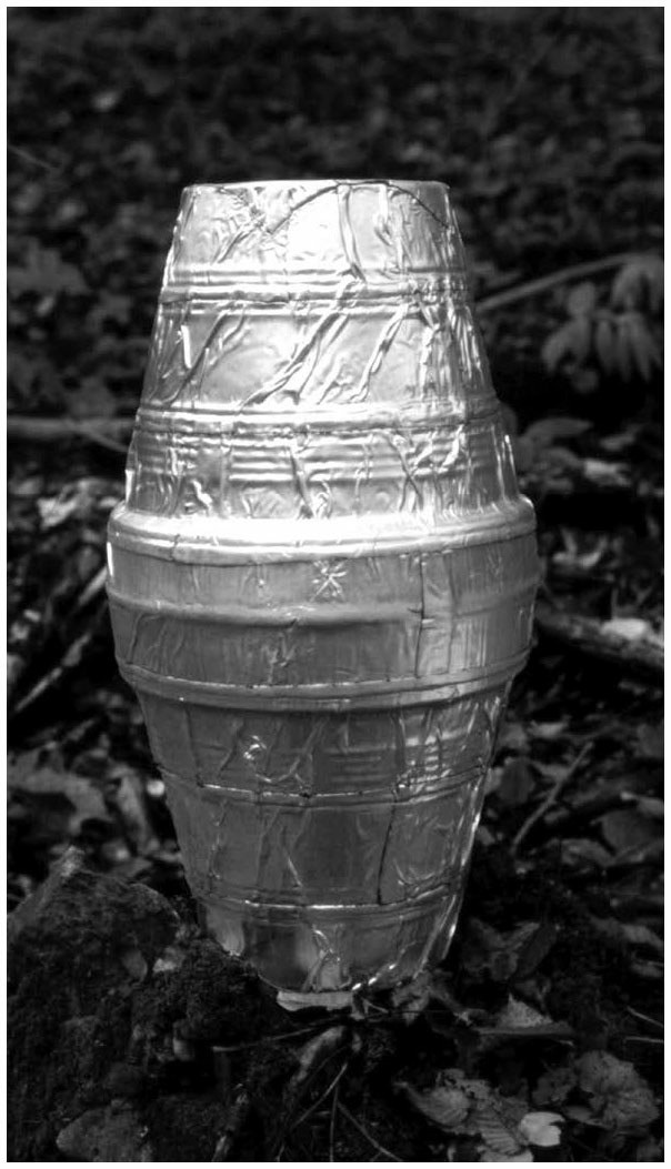 Description de l'image par IA : Tasse en plastique recouverte de papier aluminium posée sur une surface extérieure.
