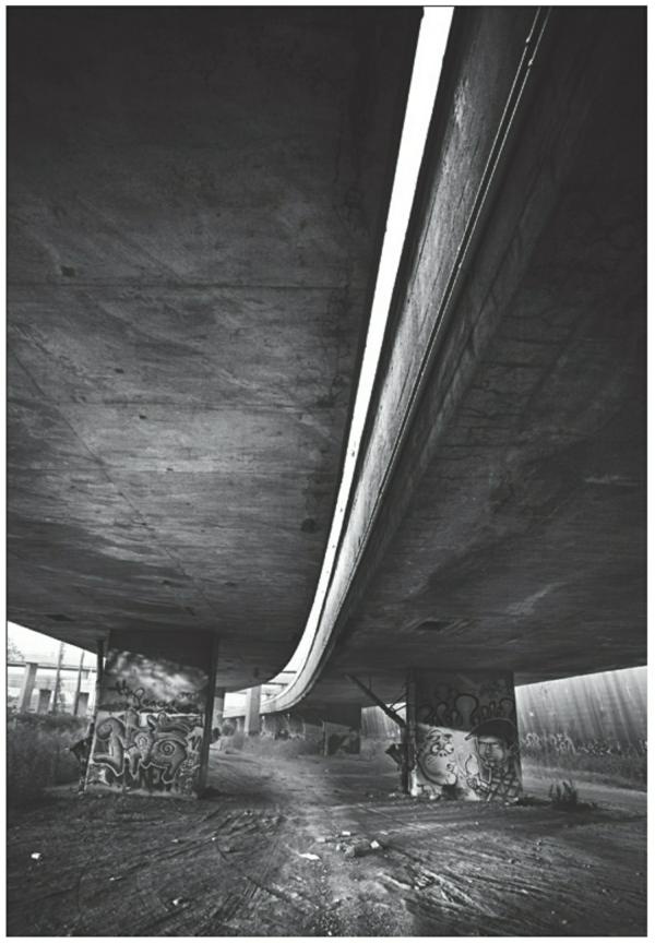 Description de l'image par IA : Sous un pont en béton, des graffitis ornent les murs, lumière filtrant des côtés.