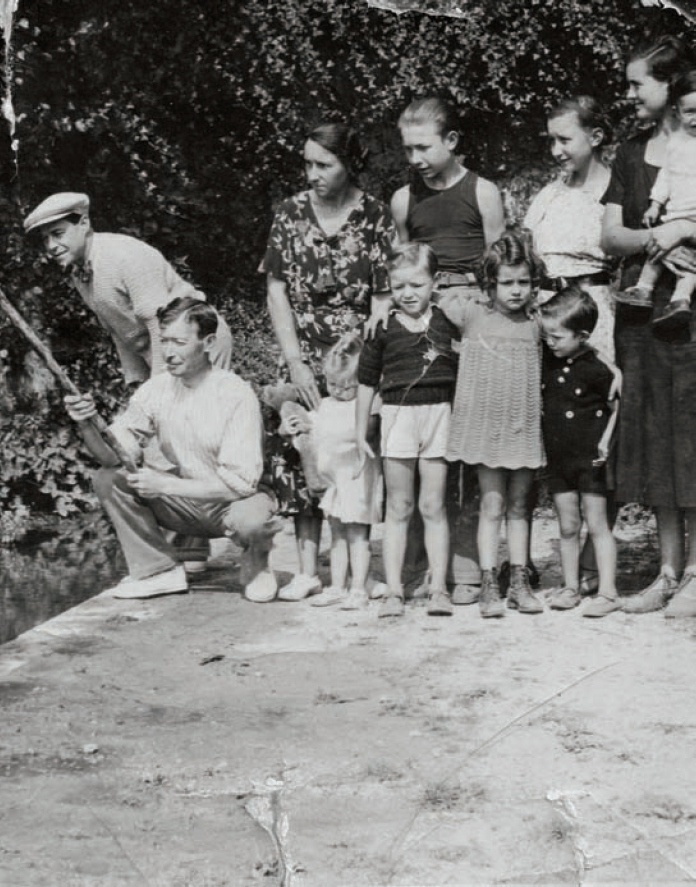 Description de l'image par IA : Groupe familial en vacances, enfants et adultes posent devant un mur de verdure.