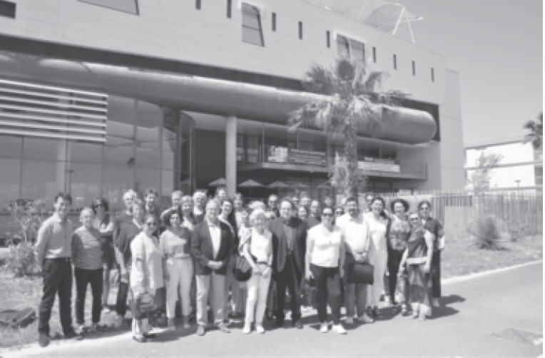 Description de l'image par IA : Groupe de personnes devant un bâtiment moderne avec palmier.