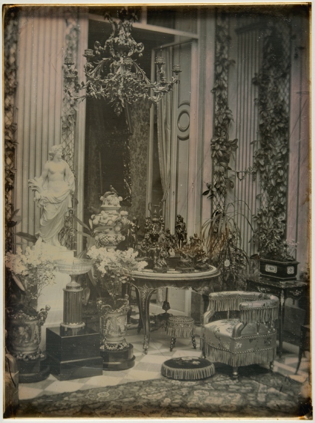Description de l'image par IA : Salle ornée avec statue, meubles, vases et plantes.