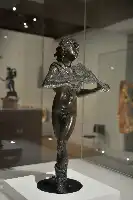 Description de l'image par IA : Sculpture en bronze d'Orphée, museau de lion, bras levés, dans une vitrine de musée.