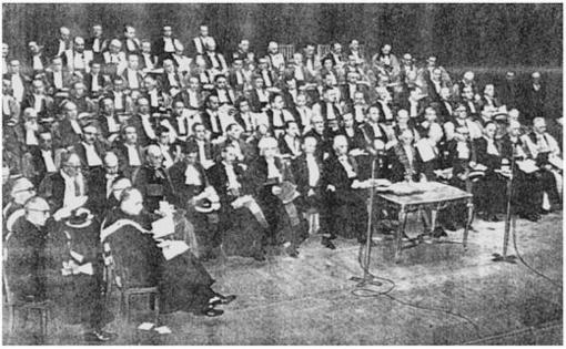 Description de l'image par IA : Nombreux universitaires en toge sur scène, entourant Gaston Berger et le recteur Michel Souriau.