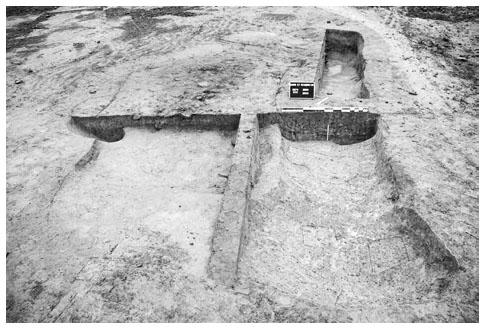 Description de l'image par IA : Fouille archéologique montrant deux structures rectangulaires en terre.