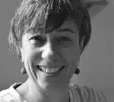 Description de l'image par IA : Photo en noir et blanc d'une femme souriant, cheveux courts, boucles d'oreilles visibles.